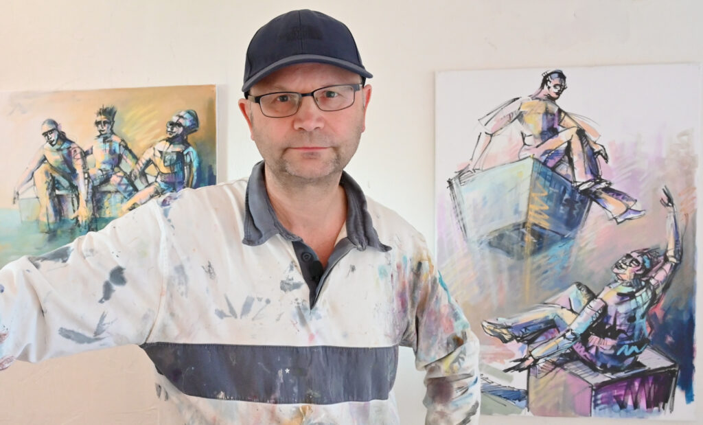 ©Frank Engel steht vor zwei Bildern im Atelier in Hamburg